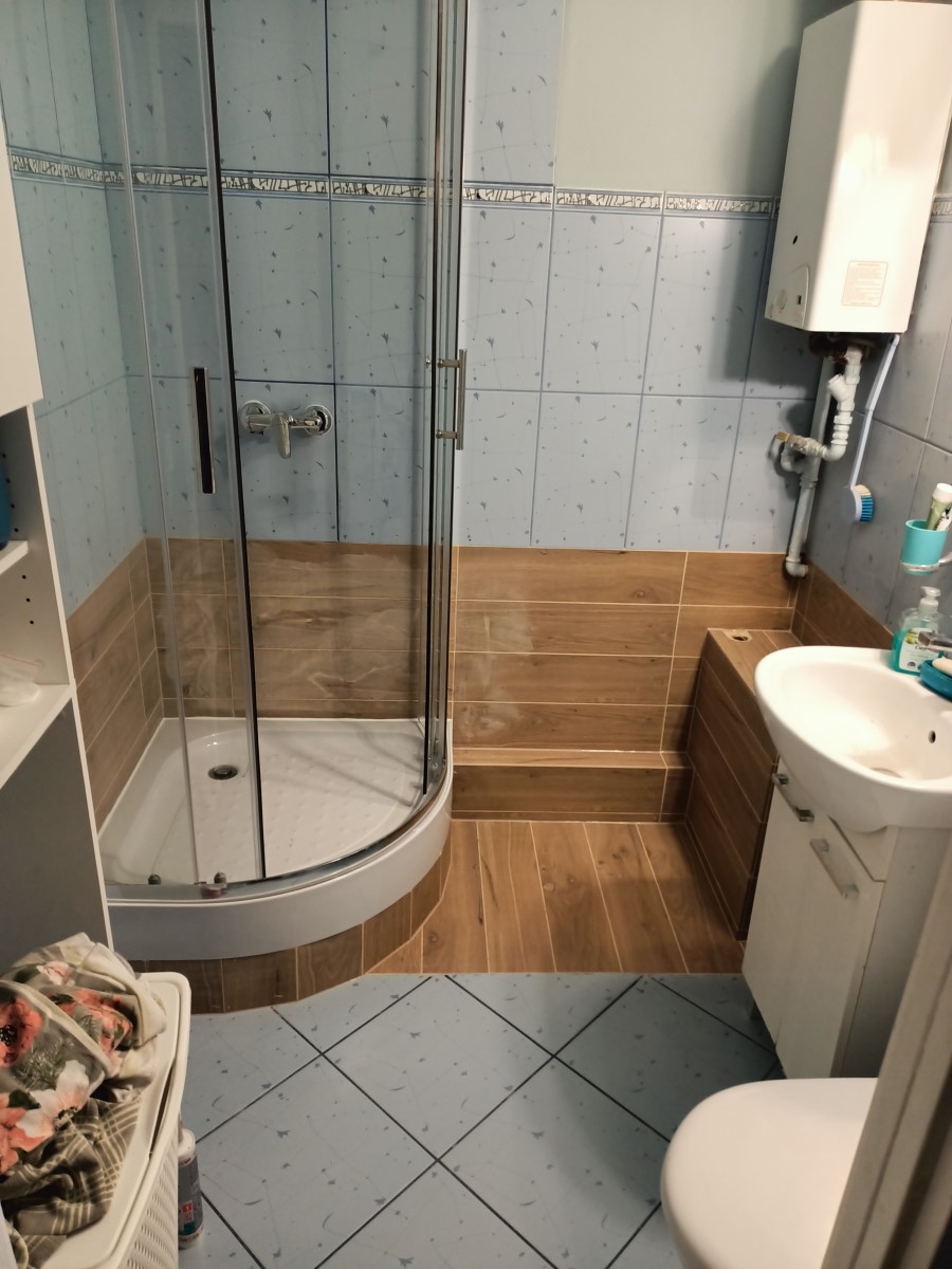 łazienka z kabiną prysznicową, piecykiem gazowym, i glazurą o wzorze drewna