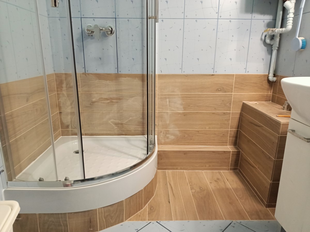 łazienka z kabiną prysznicową, piecykiem gazowym, i glazurą o wzorze drewna