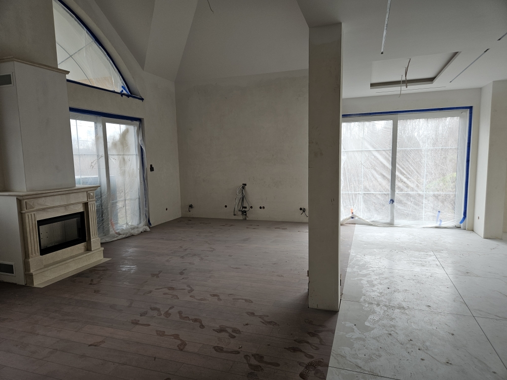 salon z kremowym marmurowym kominkiem i wielkimi oknami ze szprosami