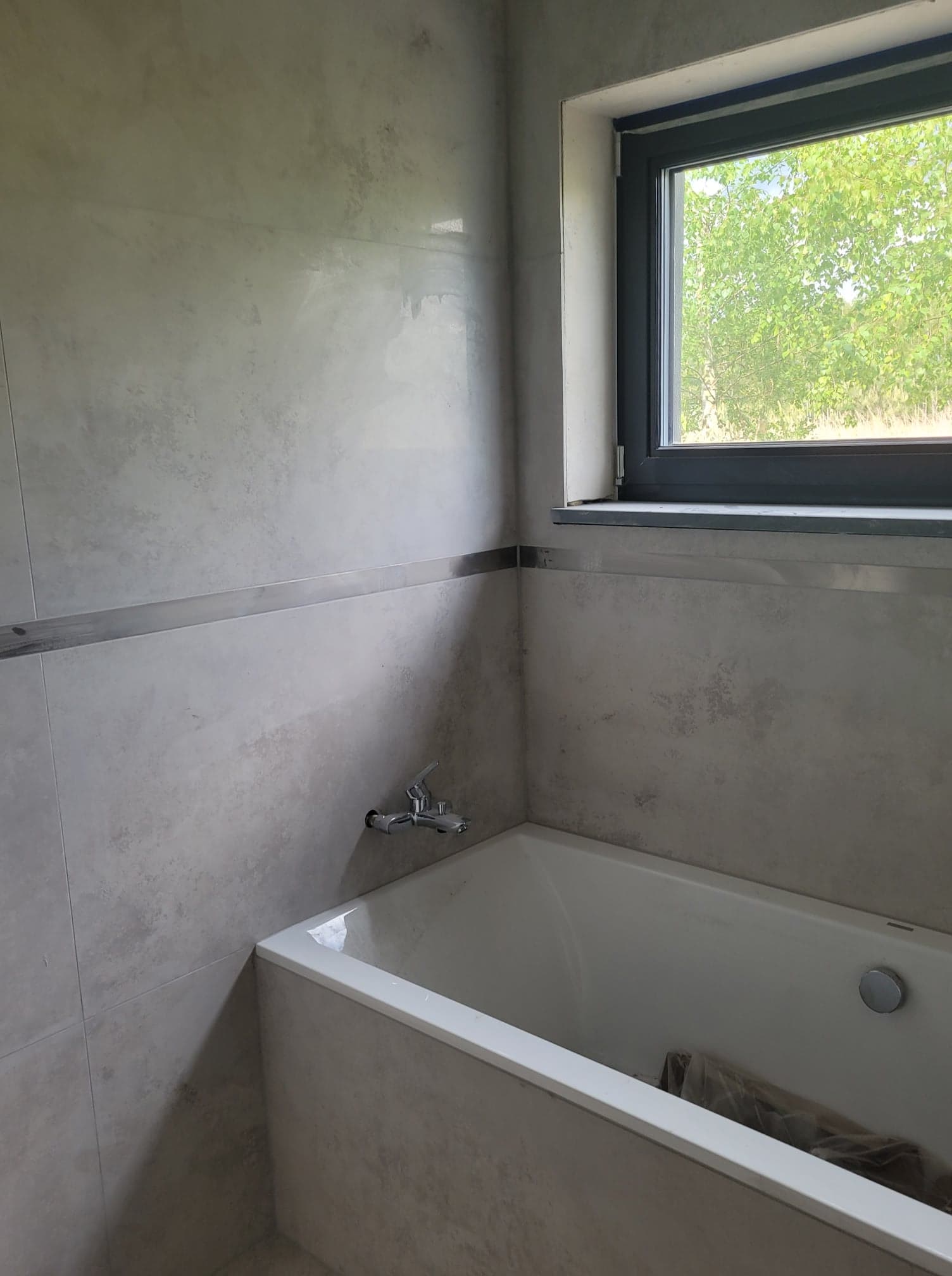 łazienka z oknem, wanną i jasną glazurą